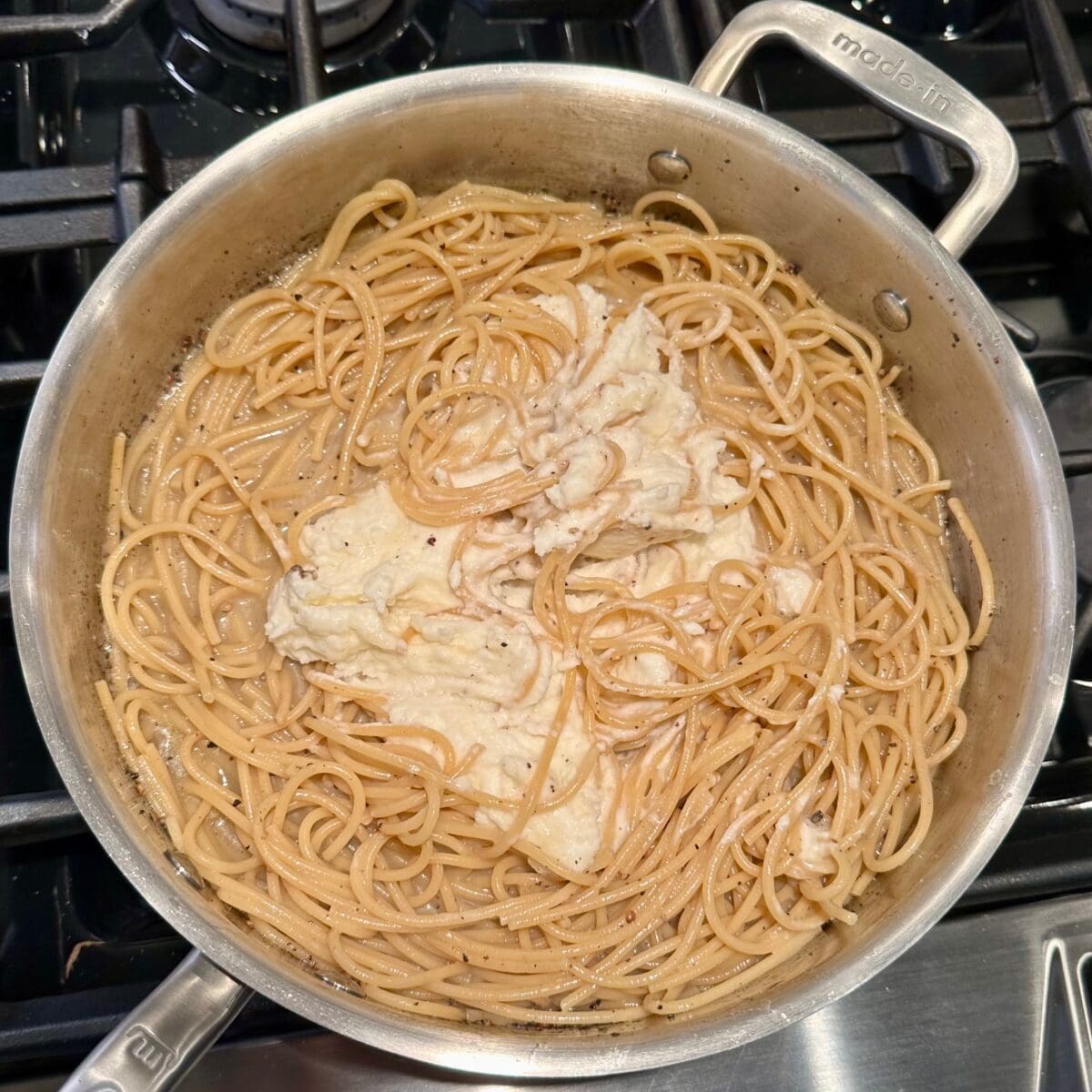 adding cheese to the cacio e pepe