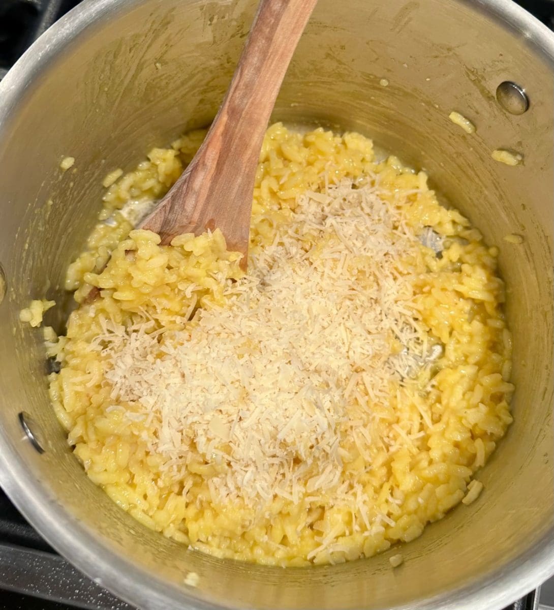 finishing the cheesy saffron restaurant risotto